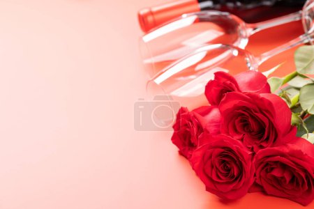 Foto de Tarjeta de San Valentín con vino, rosas y caja de regalo. Sobre fondo rojo con espacio para tus saludos - Imagen libre de derechos