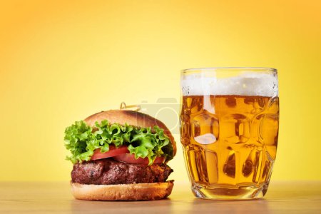 Téléchargez les photos : Beer mug and hamburger over color background - en image libre de droit