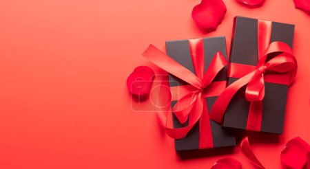 Photo for Valentines day card with gift boxes and rose flower petals. On red background with space for your greetings - Royalty Free Image