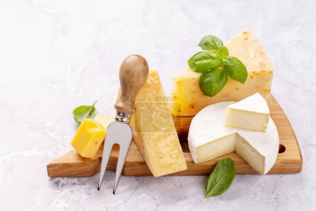 Foto de Various cheese on board and cheese fork - Imagen libre de derechos