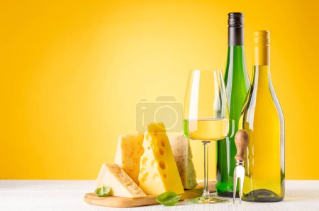Foto de Various cheese on board and white wine. Over yellow background with copy space - Imagen libre de derechos