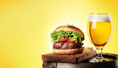 Téléchargez les photos : Tirant d'eau verre à bière et hamburger sur baril en bois. Avec espace de copie - en image libre de droit