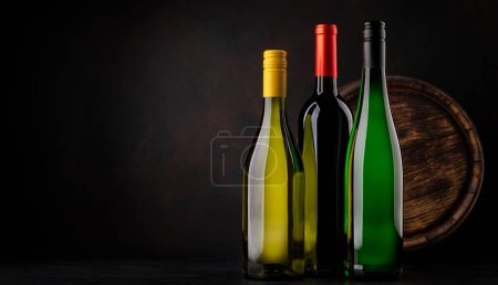 Foto de White and red wine bottles in front of wine barrel with copy space - Imagen libre de derechos