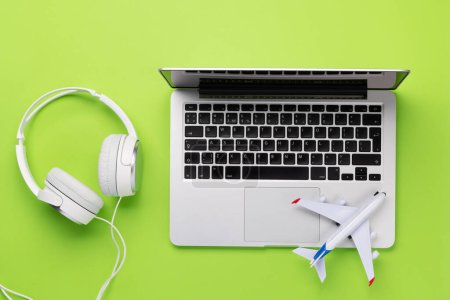 Foto de Travel and online booking concept. Laptop and airplane on green desk - Imagen libre de derechos
