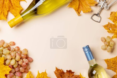 Téléchargez les photos : White wine bottles, grapes and autumn leaves. Flat lay with copy space - en image libre de droit