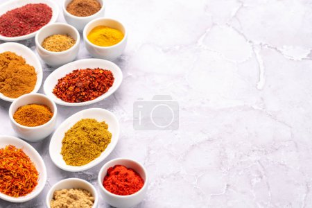 Foto de Various dried spices in small bowls on stone table - Imagen libre de derechos