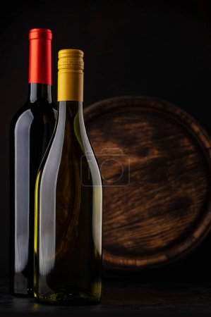 Téléchargez les photos : White and red wine bottles in front of wine barrel - en image libre de droit