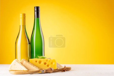 Photo for Various cheese on board and white wine. Over yellow background with copy space - Royalty Free Image