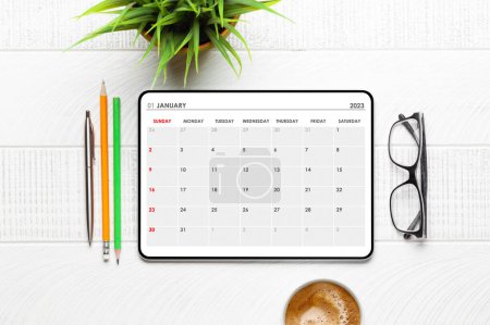 Photo for Tablet with calendar app, coffee cup and office supplies on desk. Top view flat lay - Royalty Free Image
