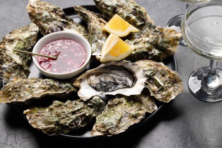 Photo for Fresh oysters with sauce and lemons. With glass of sparkling wine - Royalty Free Image