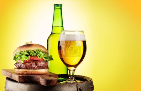 Téléchargez les photos : Tirant d'eau verre à bière, bouteille et hamburger sur baril en bois. Avec espace de copie - en image libre de droit
