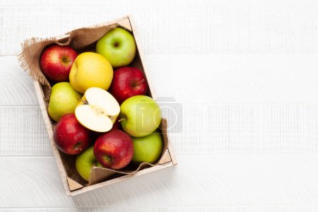 Téléchargez les photos : Fruits de pomme mûrs colorés en boîte sur une table en bois. Vue du dessus plat avec espace de copie - en image libre de droit