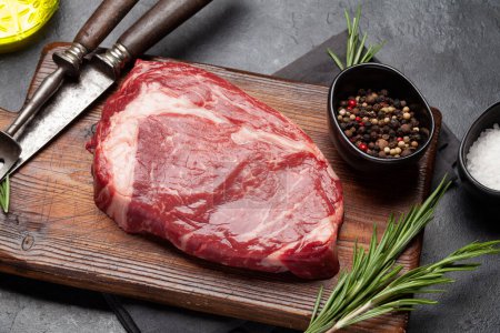 Téléchargez les photos : Raw ribeye steak on cutting board. Barbecue cooking - en image libre de droit