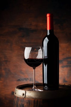Photo for Red wine glass and wine bottle on old wooden barrel. With copy space on wooden background - Royalty Free Image