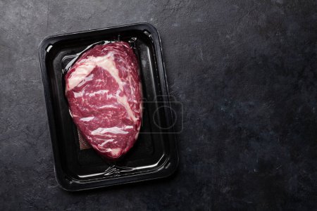 Foto de Vacuum packed beef steak. Raw ribeye steak. Top view flat lay with copy space - Imagen libre de derechos