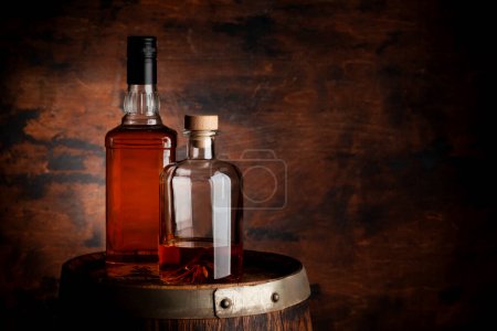 Foto de Bottles of whiskey on the old barrel. With copy space on wooden background - Imagen libre de derechos