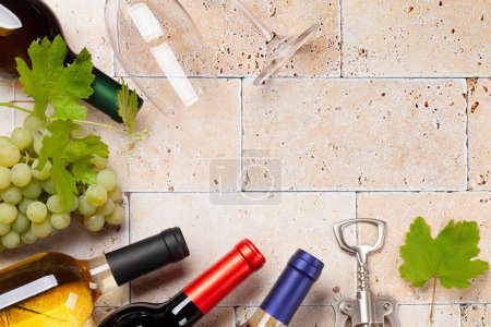 Foto de Varias botellas de vino, vasos y sacacorchos en la mesa de piedra. Piso con espacio de copia - Imagen libre de derechos