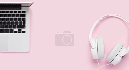 Foto de Headphones and laptop on pink background. Flat lay with copy space - Imagen libre de derechos