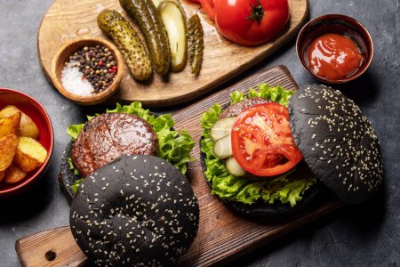 Téléchargez les photos : Homemade beef burgers with black buns and french fries - en image libre de droit