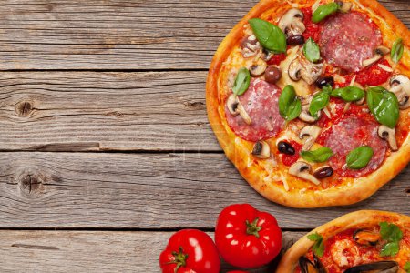 Photo for Italian cuisine. Pepperoni and seafood pizza. Flat lay on wooden table with copy space - Royalty Free Image