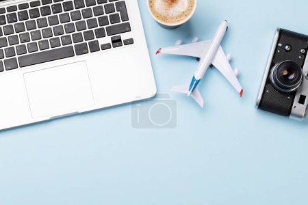 Foto de Concepto de viaje y reserva en línea. Ordenador portátil y avión en escritorio azul con espacio para copiar - Imagen libre de derechos