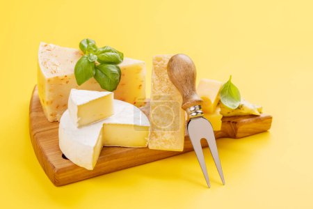 Photo for Various cheese on board and cheese fork - Royalty Free Image