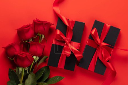 Foto de Tarjeta de San Valentín con cajas de regalo y flores rosadas. Sobre fondo rojo - Imagen libre de derechos