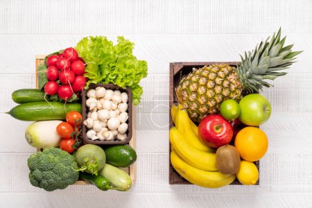 Téléchargez les photos : Boîtes en bois pleines de légumes et de fruits sains. Pose plate - en image libre de droit