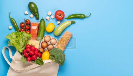 Téléchargez les photos : Sac plein d'aliments sains sur fond bleu. Pose plate avec espace de copie - en image libre de droit