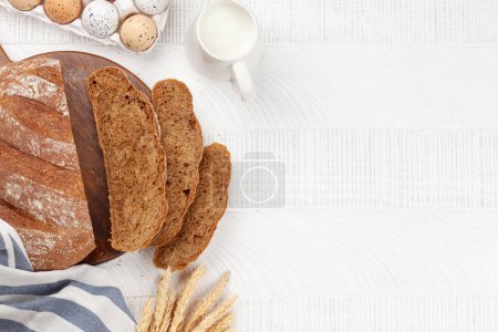 Téléchargez les photos : Homemade bread and ingredients on wooden table. Flat lay with copy space - en image libre de droit