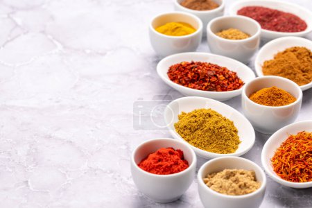 Téléchargez les photos : Various dried spices in small bowls on stone table - en image libre de droit