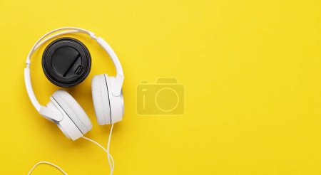 Foto de Headphones and coffee cup on yellow background. Flat lay with copy space - Imagen libre de derechos
