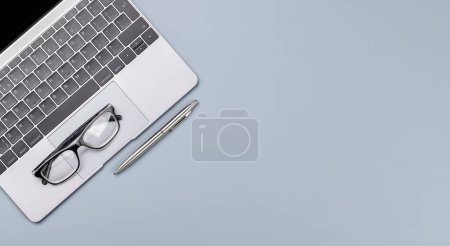 Photo for Top view business office desk with laptop, office supplies and eyeglasses. Flat lay workspace with sunny light and copy space - Royalty Free Image