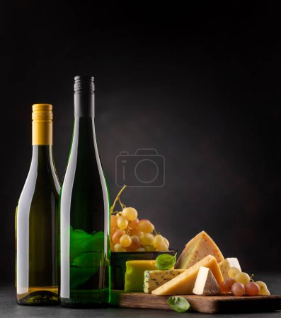 Téléchargez les photos : Various cheese on board and white wine. Over dark background with copy space - en image libre de droit