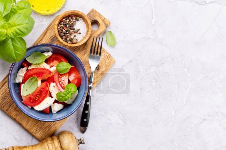 Photo for Caprese salad with ripe tomatoes, mozzarella cheese and garden basil. Flat lay with copy space - Royalty Free Image