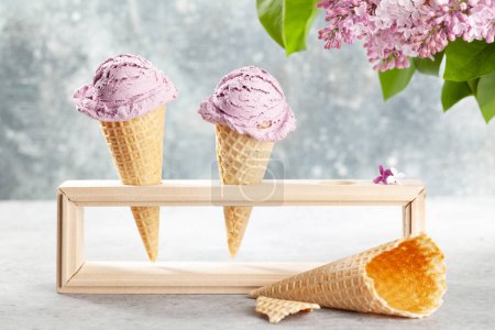 Téléchargez les photos : Crème glacée aux baies sundae aux cônes de gaufres et fleurs lilas - en image libre de droit