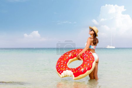 Photo for Beautiful young woman with inflatable donut ring relaxing on sea beach. Summer vacation. With copy space - Royalty Free Image