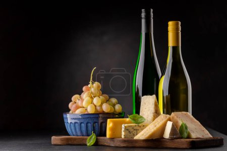 Foto de Various cheese on board and white wine. Over dark background with copy space - Imagen libre de derechos