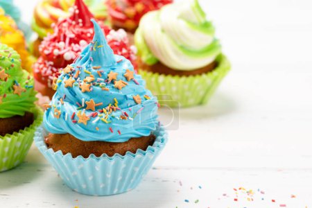Téléchargez les photos : Cupcakes colorés sur table en bois. Avec espace de copie - en image libre de droit