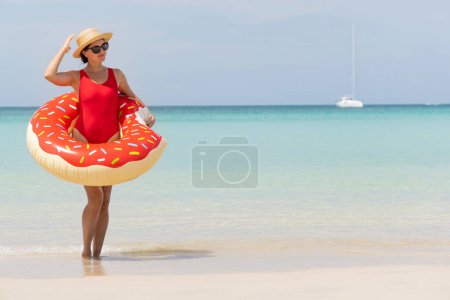 Foto de Beautiful young woman with inflatable donut ring relaxing on sea beach. Summer vacation. With copy space - Imagen libre de derechos