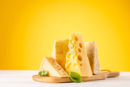 Photo for Various cheese on board. Over yellow background with copy space - Royalty Free Image