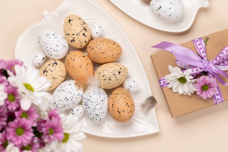 Photo for Gift box, Easter eggs and flowers on a beige background. Flat lay - Royalty Free Image