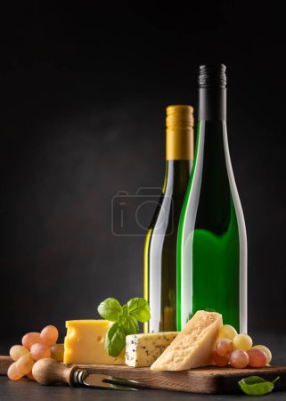 Foto de Various cheese on board and white wine. Over dark background with copy space - Imagen libre de derechos