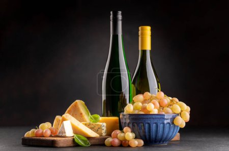 Téléchargez les photos : Various cheese on board and white wine. Over dark background with copy space - en image libre de droit