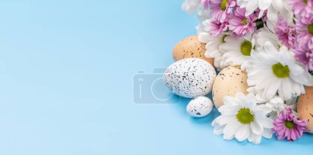 Photo for Easter eggs and flower bouquet on a blue background with space for your greetings. Flat lay - Royalty Free Image