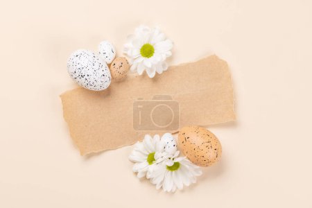 Foto de Huevos de Pascua y flores sobre un fondo beige con espacio para sus saludos. Puesta plana - Imagen libre de derechos