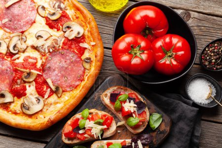 Téléchargez les photos : Cuisine italienne. Pizza pepperoni, tomates et toasts antipasto. Poser à plat sur une table en bois - en image libre de droit