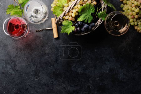 Foto de Copas de vino, botellas y uvas en cesta. Piso con espacio de copia - Imagen libre de derechos