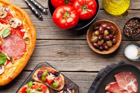 Téléchargez les photos : Cuisine italienne. Pizza pepperoni, olives et toasts antipasto. Pose plate sur table en bois avec espace de copie - en image libre de droit