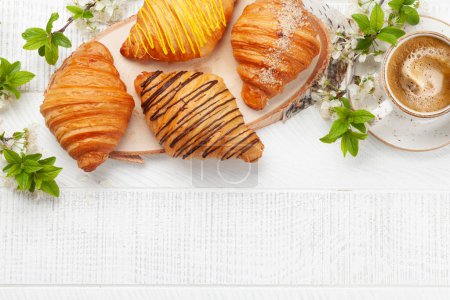 Foto de Varios croissants y taza de café sobre tabla de madera. Desayuno francés. Vista superior plano con espacio de copia - Imagen libre de derechos